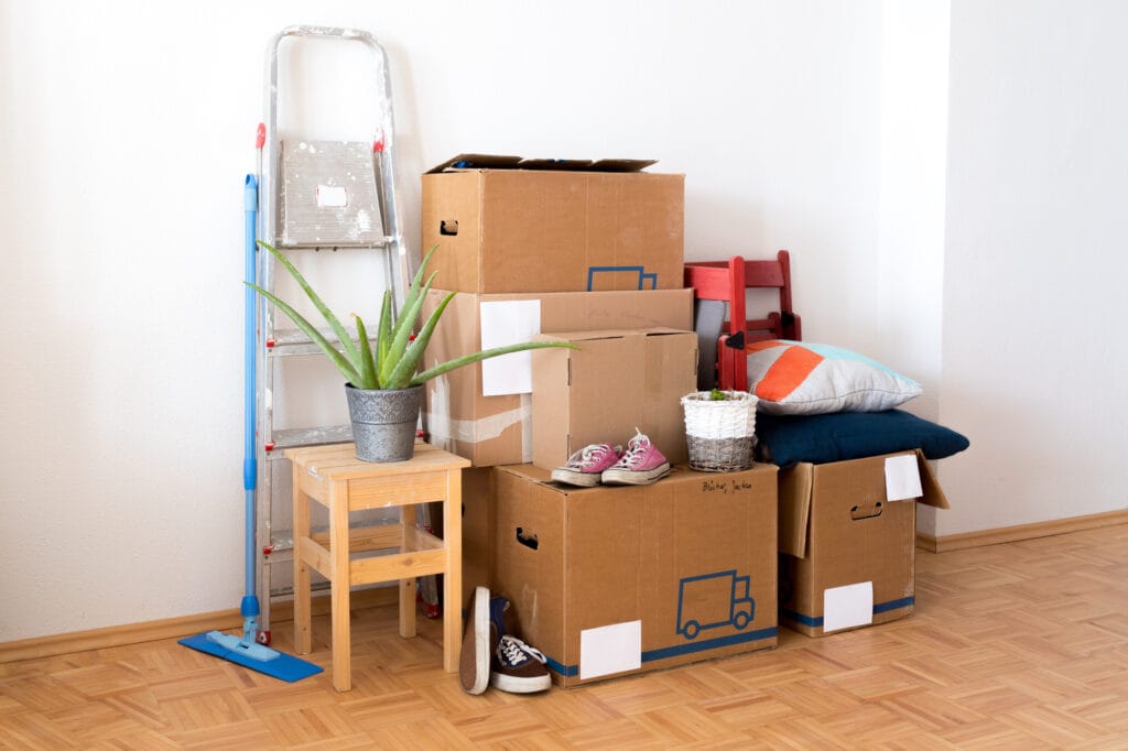 Tidy pile of moving boxes and personal items alongside cleaning supplies, showcasing Kenner Cleaning Services' comprehensive move out cleaning services.